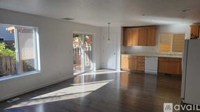 Beaverton house for rent - A spacious living room with wooden floors and a kitchen area in the background.