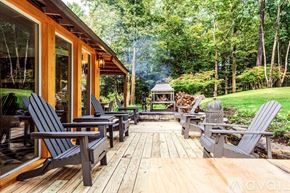 Woodstock house for rent - A wooden deck with chairs and a gazebo in a lush green forest.