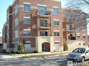 Chicago apartment for rent - A red brick apartment building with a silver car parked in front.