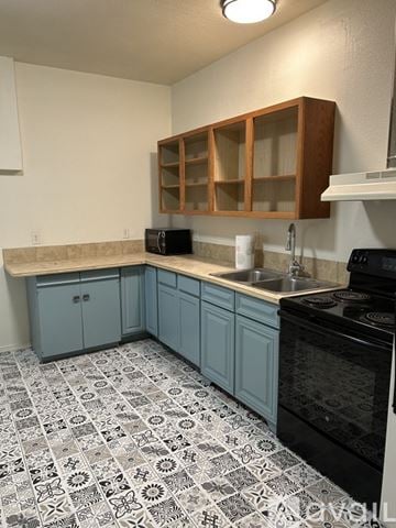 Twin Falls apartment for rent - A kitchen with a black oven and blue cabinets.