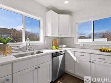 Seattle apartment for rent - A modern kitchen with white cabinets and a dining table set for two.