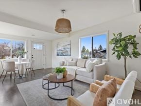 Seattle apartment for rent - A bedroom with a white bed and a window showing greenery outside.