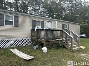 Leonardtown house for rent - A mobile home with a deck and a white fence.