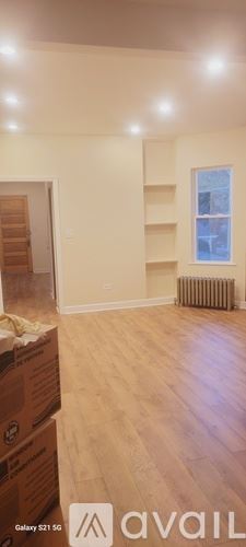 Chicago apartment for rent - A room with wooden floors and a window with a radiator to the side.