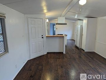 Lago Vista house for rent - A room with wooden floors and white walls, with a door on the left and a kitchenette in the middle.