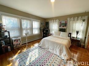 Chelmsford condo for rent - A bedroom with a bed, a chair, a bookshelf, and a window with blinds.