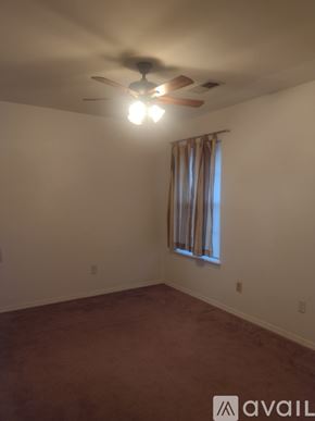 Yukon house for rent - A room with a ceiling fan and a window with curtains.