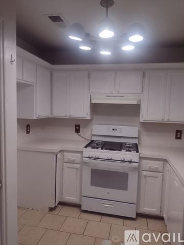 Yukon house for rent - A kitchen with white cabinets and a white stove top oven.