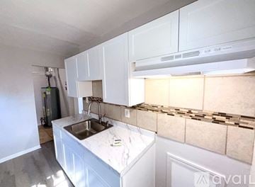 Warren house for rent - A kitchen with white cabinets and a marble countertop.