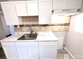 Warren house for rent - A kitchen with white cabinets and a marble countertop.