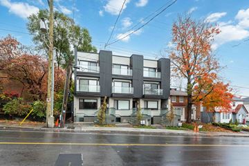 Ottawa apartment for rent - A modern building with grey and white exterior is situated on a street corner with trees showing autumn colors.