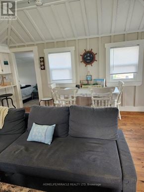 Chatham-Kent (Blenheim) house for rent - A grey couch with a blue pillow is in the middle of a room with white walls and a wooden floor.