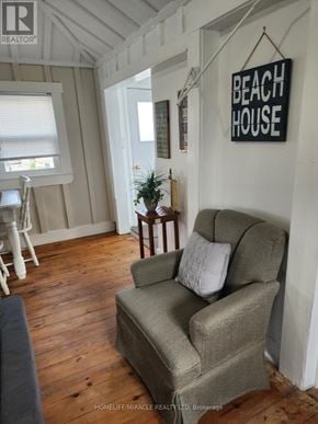Chatham-Kent (Blenheim) house for rent - A grey couch with a white pillow sits in a room with wooden floors and a sign that says "Beach House".