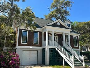 Pawleys Island house for rent - A two-story house with a white garage door and a green staircase railing.