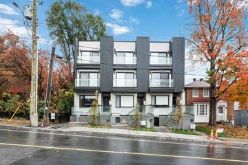 Ottawa apartment for rent - A modern building with a grey facade is situated on a street with trees showing autumn colors.