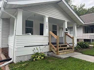 Omaha apartment for rent - A white house with a porch and a wooden railing.