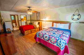 Buchanan house for rent - A bedroom with a bed covered in a pink and blue quilt.