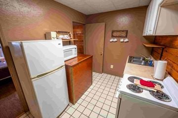 Buchanan house for rent - A kitchen with a white refrigerator, a stove with a red pot on it, and a brown counter.