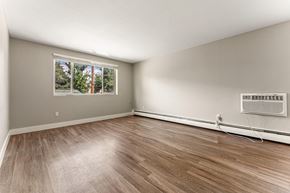 Denver apartment for rent - A room with a window and a wall-mounted air conditioner unit.