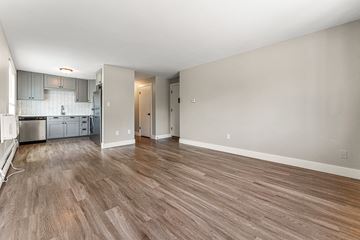 Denver apartment for rent - A room with wooden flooring and a kitchen area in the background.