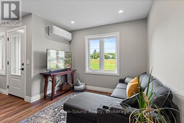 Northern Bruce Peninsula townhouse for rent - A living room with a grey couch and a window showing a view of a field.