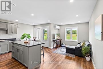 Northern Bruce Peninsula townhouse for rent - A living room with a grey couch and a window showing a view of a field.