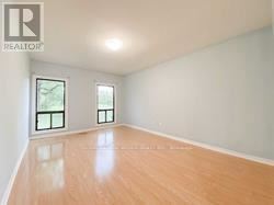 Richmond Hill house for rent - A large empty room with wooden floors and two windows.