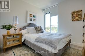Oshawa (O'neill) condo for rent - A bedroom with a bed, nightstand, lamp, and artwork.