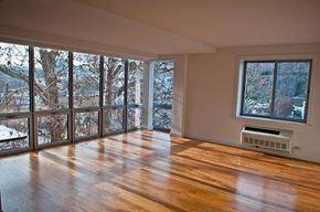 Bronx apartment for rent - an empty living room with a wood floor and large windows