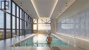 Kitchener condo for rent - A woman is sitting in a pool in a large room with a marble wall.