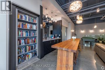 Oshawa (O'neill) condo for rent - A modern living room with a wooden table and a bookshelf filled with books.