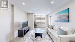 Belleville (Thurlow Ward) house for rent - A living room with a white couch, a television, and a painting on the wall.