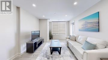 Belleville (Thurlow Ward) house for rent - A living room with a white couch, a television, and a painting on the wall.