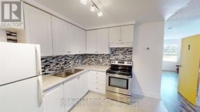 Oshawa (Lakeview) house for rent - A kitchen with white cabinets and a black and white tiled backsplash.