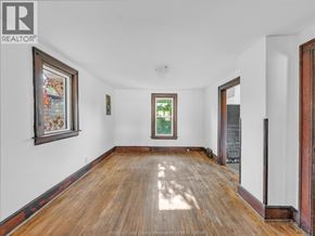 Windsor duplex for rent - A room with wooden floors and white walls, with a window showing greenery outside.