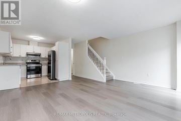 Waterloo townhouse for rent - A spacious kitchen with white cabinets and a staircase leading to the upper floor.