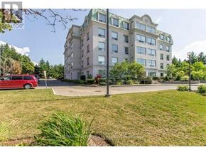 Waterloo condo for rent - A red car is parked on the left side of a street in front of a large building.