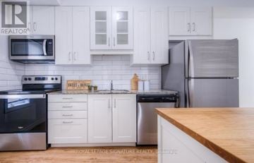 Kitchener condo for rent - A kitchen with white cabinets and a wooden counter top.