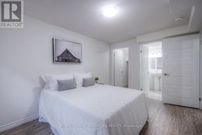 Kitchener condo for rent - A bedroom with a bed, a picture on the wall, and a door leading to another room.
