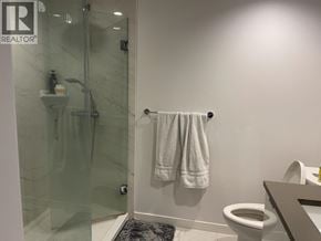 Richmond apartment for rent - A bathroom with a toilet, a glass shower stall, and a towel rack.