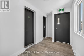 Chatham-Kent (Wallaceburg) multi-family for rent - A hallway with two doors and a green exit sign above the right door.