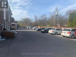 St. Catharines (Glendale/Glenridge) fourplex for rent - A parking lot with cars and a building with a sign that says RE/MAX Garden City Realty Inc. Brokerage.