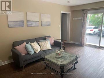 St. Catharines (Glendale/Glenridge) fourplex for rent - A living room with a grey couch and a glass coffee table.