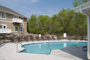 Janesville apartment for rent - A swimming pool surrounded by chairs and trees.