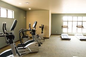 Janesville apartment for rent - A gym with treadmills, elliptical machines, and a weight machine.