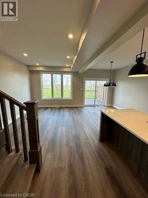 Ingersoll townhouse for rent - A well-lit room with wooden floors and a large window.