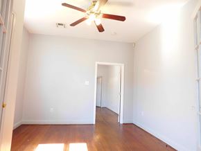 New Orleans apartment for rent - A room with a ceiling fan and wooden floors.