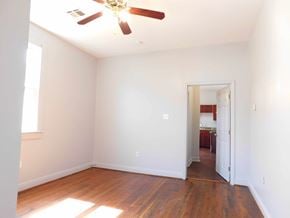 New Orleans apartment for rent - A room with a ceiling fan and wooden floors.
