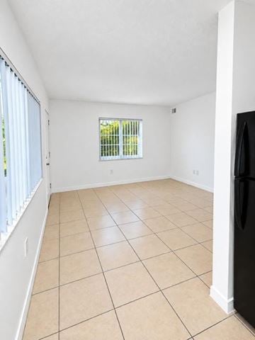 Fort Lauderdale apartment for rent - A black refrigerator sits in a kitchen with beige tiled floors and white walls.