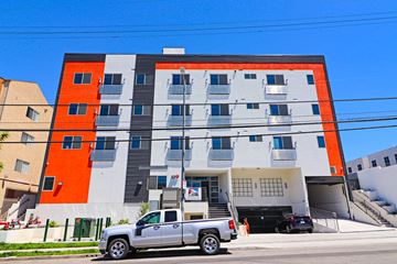 Los Angeles apartment for rent - A modern building with a white and orange facade has a silver truck parked in front of it.